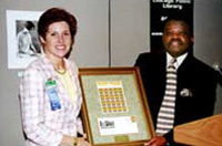 During a National Literacy Landmark award ceremony held July 7, Chicago Public Library Commissioner Mary Dempsey is presented with a framed plate of the Library's stamp and a commemorative envelope by Rufus Porter, postmaster of Chicago. 