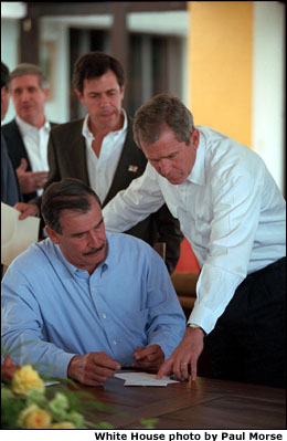 Mexican President Vicente Fox is seated. President Bush is standing next to him. White House photo by Paul Morse.