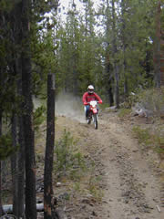 photo of motorbike rider on trail in woods showing steep terrain and woods