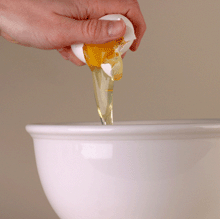 Photo of hand breaking egg into bowl.