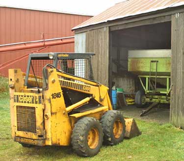 Photo 2 – Another view of the skid-steer loader, grain wagon, and machine shed.