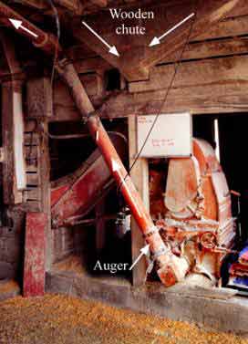 view of roller mill from inside the corncrib showing gravity fed chute and auger