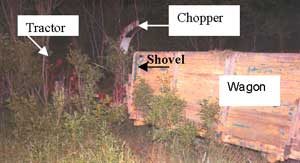 Figure 2. Tractor, chopper, trailer wagon stalled in tree line next to field.