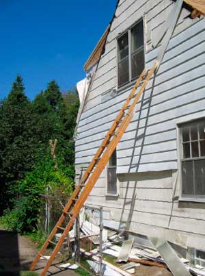 Figure 1. Siding being removed, ladder propped against fence.