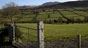 Landscape image of a rolling field with a fence in the foreground