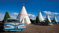 A 1950s era car and a line of white wigwams.