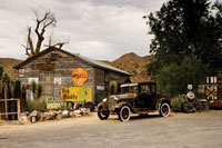 A 1920s era car in front of a wood building.