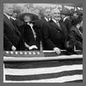 Left to right: Herbert Hoover, Mrs. Warren G. Harding, Warren G. Harding, Mrs. Herbert Hoover, ... all standing, in grandstand, at baseball game.