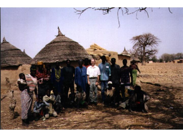 STOP team member and villagers in front of hut