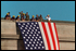 One day after terrorists used commercial airplanes to destroy the World Trade Center Towers and attack the Pentagon, firefighters take a moment to unfurl the flag over the scarred stone as inspiration for fellow rescue workers searching through the debris Sept. 12