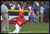 A player rounds first base as Transportation Secretary Norman Mineta umpires the first base line during the second Tee Ball game on the South Lawn on Sunday, June 3, 2001.