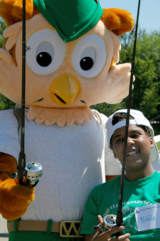 Photograph:  Woodsy the Owl poses with little boy at National Fishing and Boating Day, both holding their fishing poles.