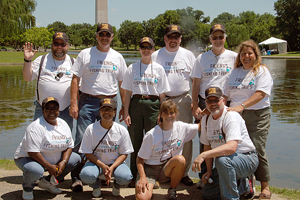 Photograph:  Voluntees take a moment for a group photo; posing in front of the "pond" with the Washington Monument in the background.