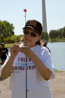 Photograph:  Volunteer helps set up a fishing pole.  Washington Monument in the back ground.