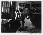 Unidentified cobbler, three-quarter length portrait, facing front, seated in shop, holding shoe on lap, Quemchi, Chile