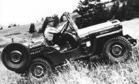 Photo of a man driving a jeep uphill in mountainous terrain.