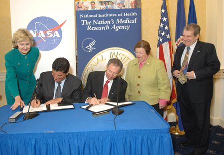 NIH Director Dr. Elias A. Zerhouni and NASA Administrator Dr. Michael D. Griffin sign an agreement making U.S. resources on the International Space Station available for NIH-funded research.  Senator Kay Bailey Hutchison (R-TX) (left), Senator Barbara Mikulski (D-MD), and NIAMS Director Dr. Stephen I. Katz witness the occasion.