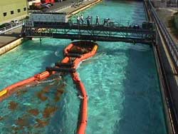 Containment boom and skimmer being tested with oil at Ohmsett--The National Oil Spill Response Test Facility.