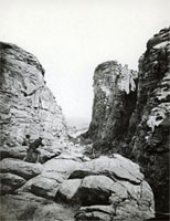 A photograph of two men on a rock, looking at Devil's Gate.