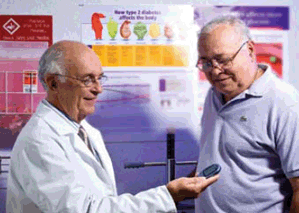 Carlos Abraira, MD, co-chair of the VA Diabetes Trial, discusses the use of a glucometer—a device that measures blood sugar—with patient Fulgencio Rodriguez at the Miami VA