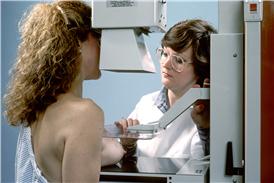 Mama derecha prensada entre las placas de un aparato para mamografía