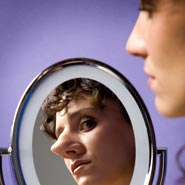 A woman looking in the mirror at her nose, which appears bigger than in real life