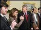 President George W. Bush stands with out-of-country Iraqi voters Thursday in the Oval Office of the White House. The President told the media later, "I was struck by how joyous they were to be able to vote for a government -- a permanent government under a new constitution." White House photo by Paul Morse