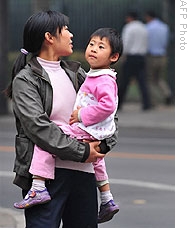 A woman carries her child in Beijing as state media reported 3 children died this month and 113 people have been sickened in southeastern China with hand, foot and mouth disease, Oct 20, 2008