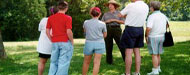 Adults and children gathered around a park ranger as she speaks to them.