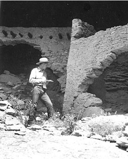 (NPS Photo) Archeologist records data at cliff dwelling site.