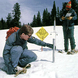 One surveyor measures the snow depth while the other records data. 