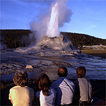 Group of four people watching geyser erupt.
