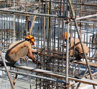 Two workers tying rebar approximately three stories above the ground in Beijing.