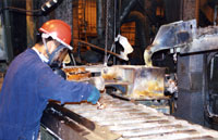 Young man is ladling molten recycled lead into billets in a lead-acid battery recovery facility.