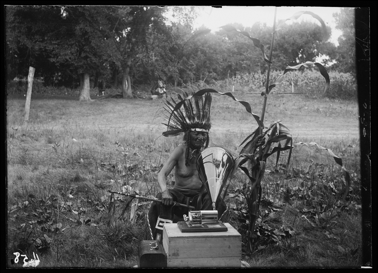Native American man speaking into a Columbia Model B 'Eagle' recorder.