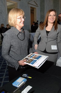 Congresswoman Biggert, co-chair of the Financial Literacy and Economic Caucus (left), picks up information on the OCC's financial literacy and customer assistance programs from Adrienne Mingione of Community Affairs.