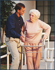 Older woman with walker assisted by younger man.