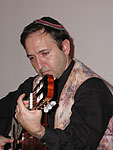 Closeup of Sephardic cantor Ramon Tasat playing his guitar