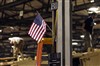 An American flag hangs as workers at the Vehicle Integration Facility work on producing MRAPs in Charleston, S.C., Jan. 18, 2008.  