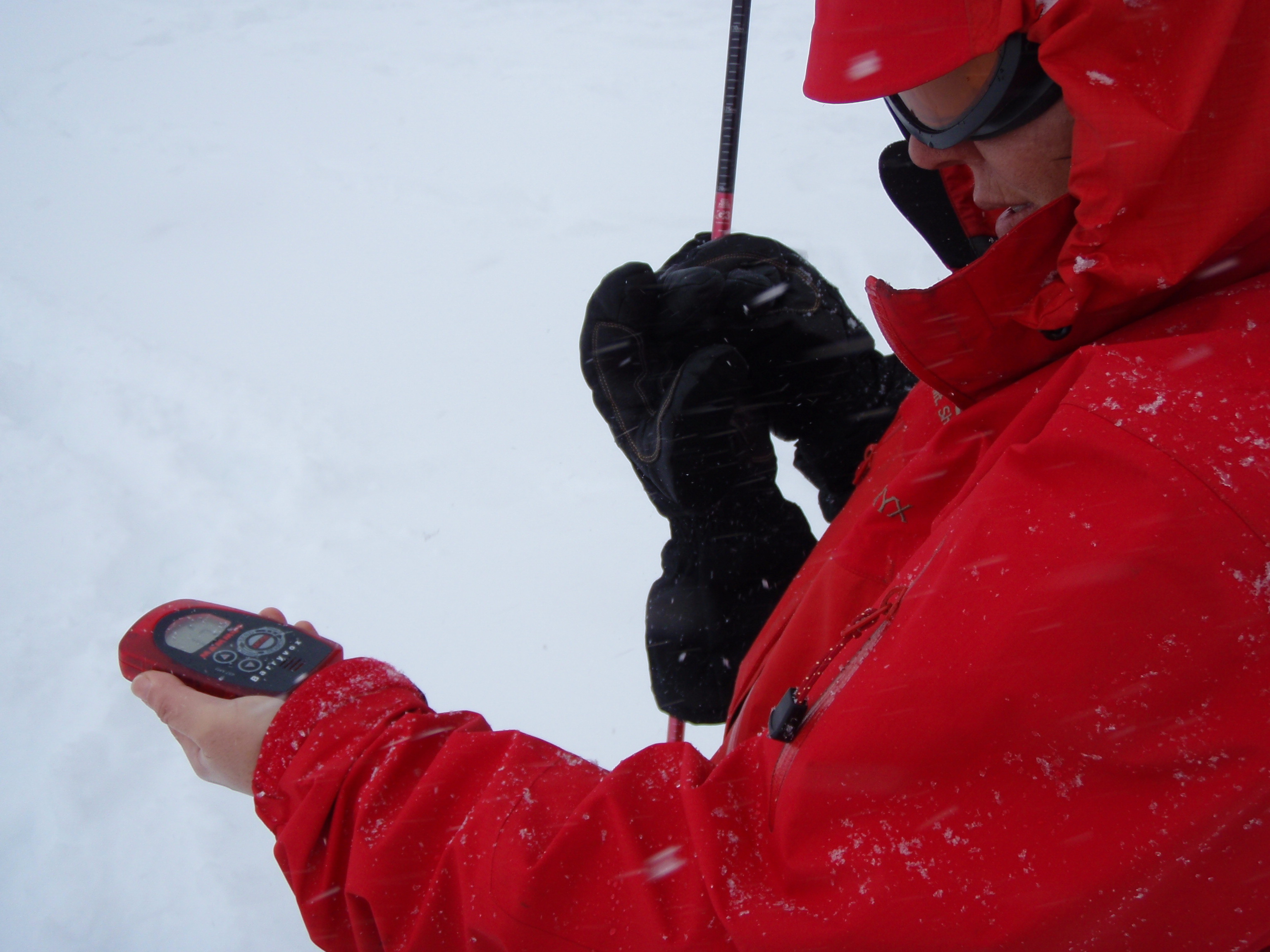 Woman practicing with her avalanche transceiver and probe in the snow.