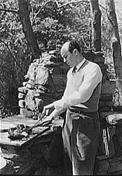 Man cutting meat while standing at a  barbeque made of stone.