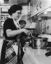 Two women in a kitchen using pressure cookers.