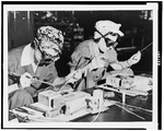 Two women wearing protective goggles at a welding bench