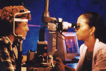 a photo of a female doctor performing laser eye therapy on a female patient.