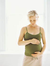 Image of pregnant Caucasian woman standing and touching her stomach.