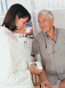 Photo of a female doctor checking the blood pressure of an older man.