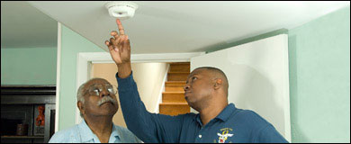 Photo: Two men testing a smoke alarm