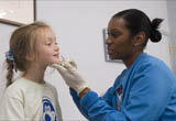7 years old girl in white t-shirt getting FluMist in her nose 