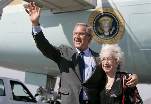 President George W. Bush waves to photographers with Freedom Corps Greeter Lucia Haas in front of Air Force One after his arriving in Phoenix, Arizona, Wednesday, Aug. 11, 2004. Hass, 73, spends two days a week as a volunteer at Surprise Senior Center in Surprise, Arizona, where she teaches English and Spanish Classes, calls Bingo games, instructs needlecraft and sewing classes and serves meals to seniors. White House photo by Eric Draper.