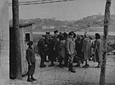 German and Lithuanian guards search Jewish women returning from forced labor outside the ghetto. Kovno, Lithuania, wartime.